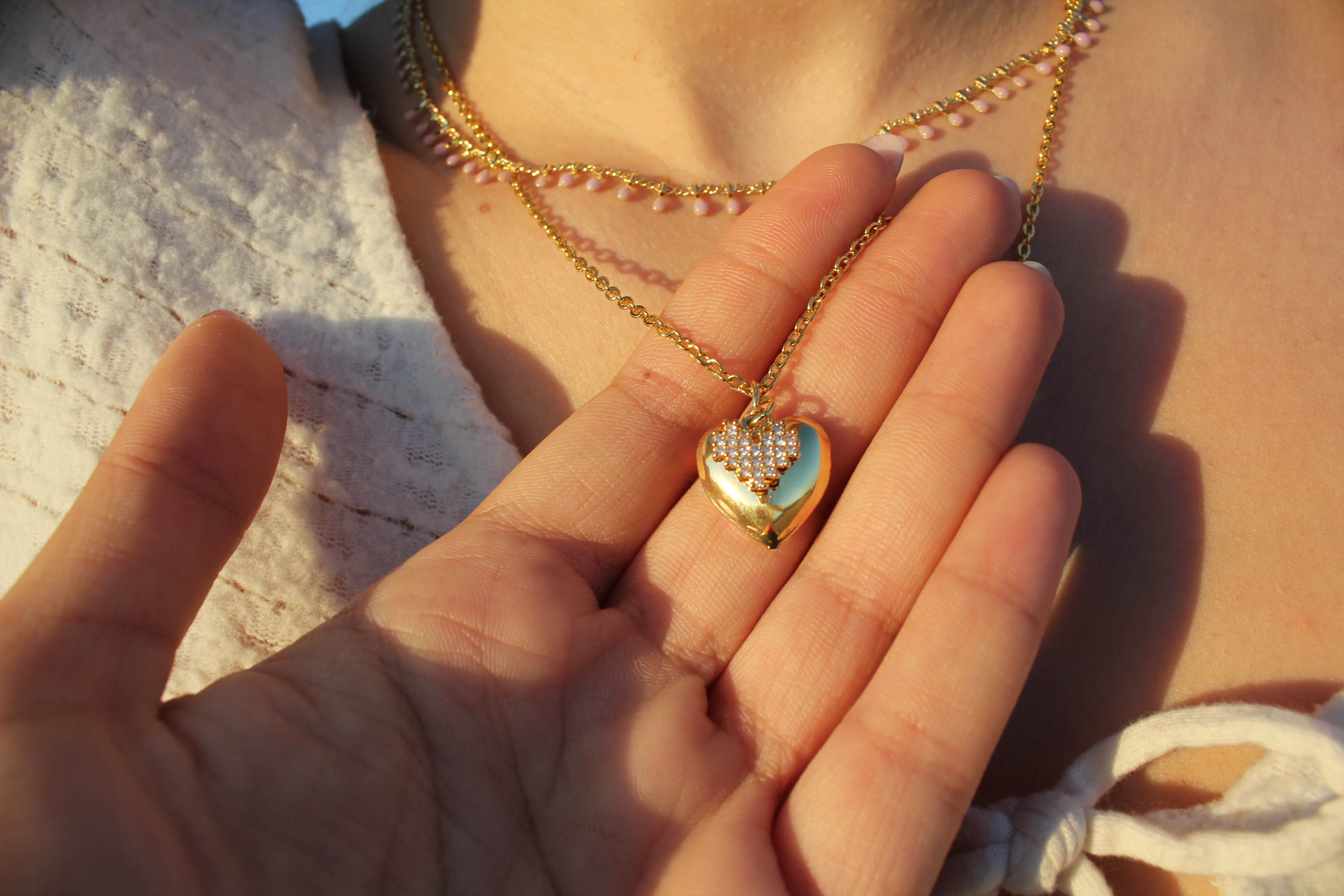 Pendentif cœur doré et strass dans une main